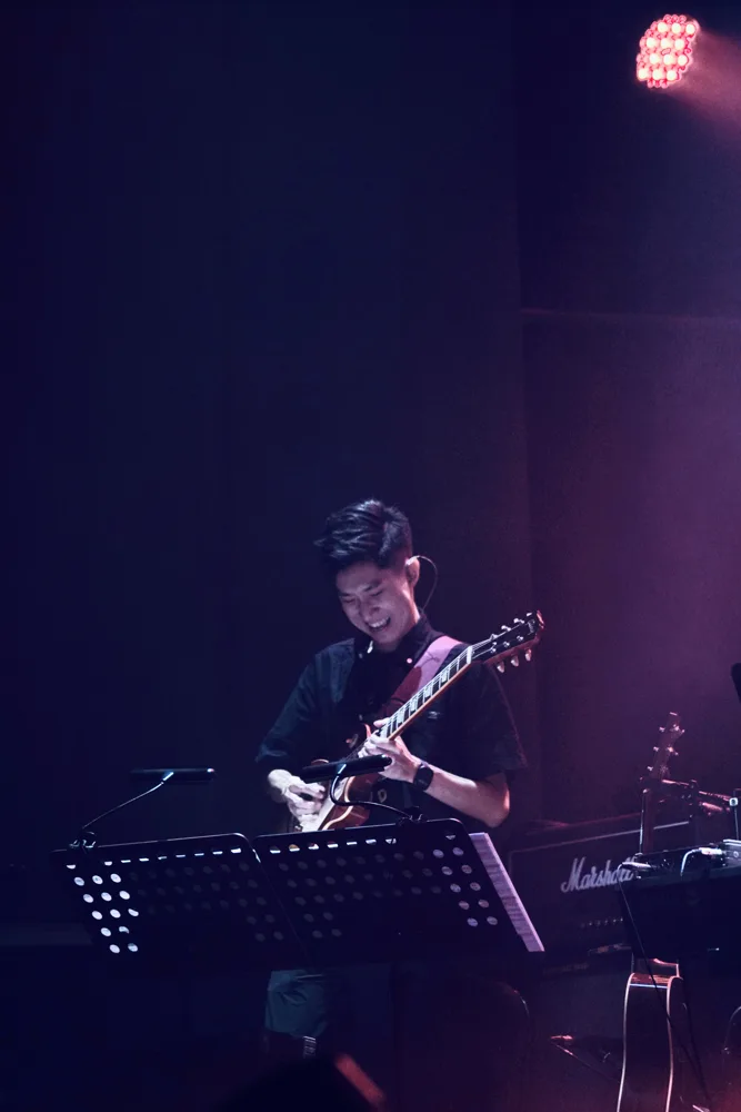 Guitarist playing electric guitar under red and purple lights