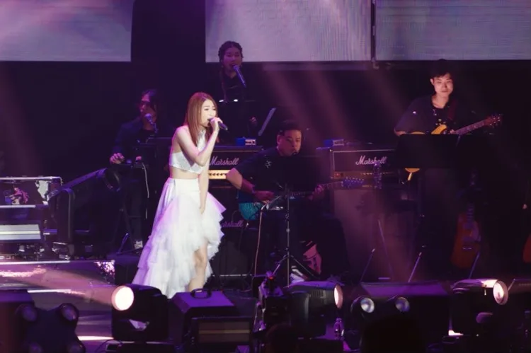 Vocalist in a white dress performing with a live band